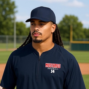 May include: A navy blue baseball coach's jacket with a zip fastening and a red and white "Mustangs Baseball 14" logo on the chest.