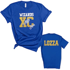 Può includere: T-shirt blu reale con testo glitterato dorato. La parte anteriore della maglietta dice "Wizards XC Mom" con una grafica di scarpa da corsa. La parte posteriore della maglietta dice "LOZZA" in glitter dorati.
