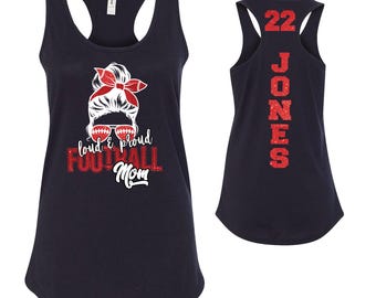 May include: Navy blue tank top with a red and white graphic of a woman with a messy bun, sunglasses, and a football. Text reads "loud & proud FOOTBALL Mom." The back of the tank top has the number "22" and the name "JONES" in red.