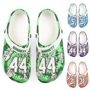 Puede incluir: Zuecos verdes y blancos con el nombre "Barrett" y el número "44" impresos. Los zuecos tienen un estampado tie-dye y gráficos temáticos de lacrosse. También se muestran pares adicionales en azul, morado y naranja con diferentes nombres y números.