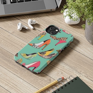 May include: A teal blue phone case with a colorful pattern of high-heeled shoes. The shoes are in various colors and patterns, including leopard print, polka dots, and stripes.