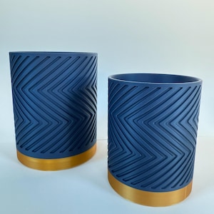 May include: Two blue ceramic planters with a gold rim and a chevron pattern.