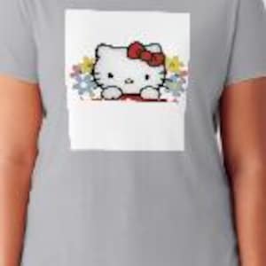 K&ouml;nnte beinhalten: Ein graues T-Shirt mit einem wei&szlig;en Aufdruck von Hello Kitty, die aus einem bunten Puzzle herausguckt.