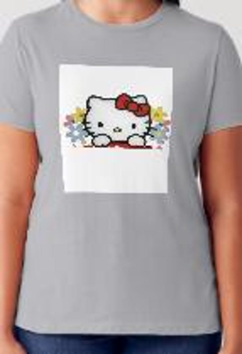 K&ouml;nnte beinhalten: Ein graues T-Shirt mit einem wei&szlig;en Aufdruck von Hello Kitty, die aus einem bunten Puzzle herausguckt.
