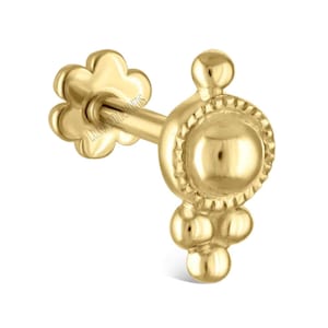 May include: A gold earring with a flower-shaped back and a decorative front. The front has a central circular design with a beaded border, and three small beads below. The earring is designed for a single ear piercing.