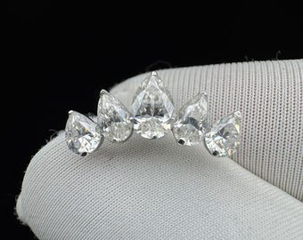 May include: A silver-toned ring featuring five pear-cut clear stones arranged in a graduated arc. The center stone is the largest, with two smaller pear-cut stones on each side, all set in a metallic band that follows the curved shape of the stones.