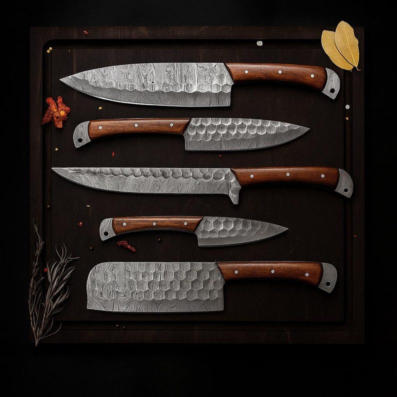 Op de afbeelding: Een set van vijf keukenmessen met houten handvatten en getextureerde lemmeten. De zilverkleurige lemmeten contrasteren met de warmbruine handvatten. De set bevat een koksmes, een schilmes en een hakmes. De messen zijn gerangschikt op een donkere snijplank.