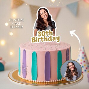 Può includere: Una torta rosa decorata con strisce verticali turchesi e viola. Ha un cake topper personalizzato con una donna sorridente e la scritta "30th Birthday". La torta è su un supporto bianco con bordo dorato. È visibile anche il testo "CUSTOM CAKE TOPPER".