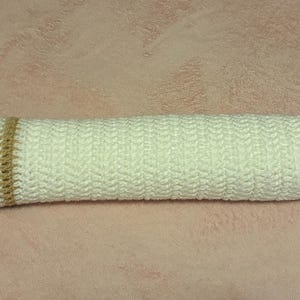 May include: A handmade crochet bolster pillow. The pillow is primarily white with a tan end and a red end. There are also tan and black stripes. The pillow is approximately 18 inches long.