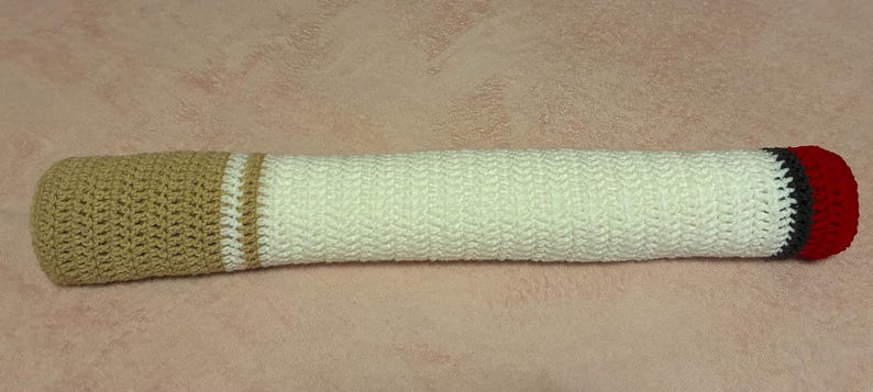 May include: A handmade crochet bolster pillow. The pillow is primarily white with a tan end and a red end. There are also tan and black stripes. The pillow is approximately 18 inches long.
