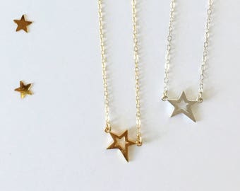 Puede incluir: Dos delicados collares con colgantes en forma de estrella. Uno es de oro y el otro de plata.