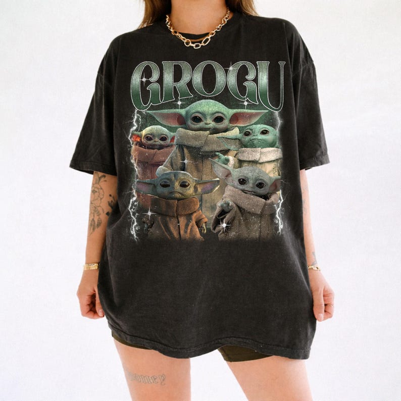 May include: Black t-shirt featuring a graphic of Grogu, also known as Baby Yoda, from The Mandalorian. The design includes multiple images of Grogu with the word "GROGU" in a green, retro-style font. The shirt has a vintage, worn look.