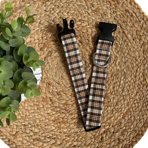May include: A brown and white plaid dog collar with black plastic buckles.
