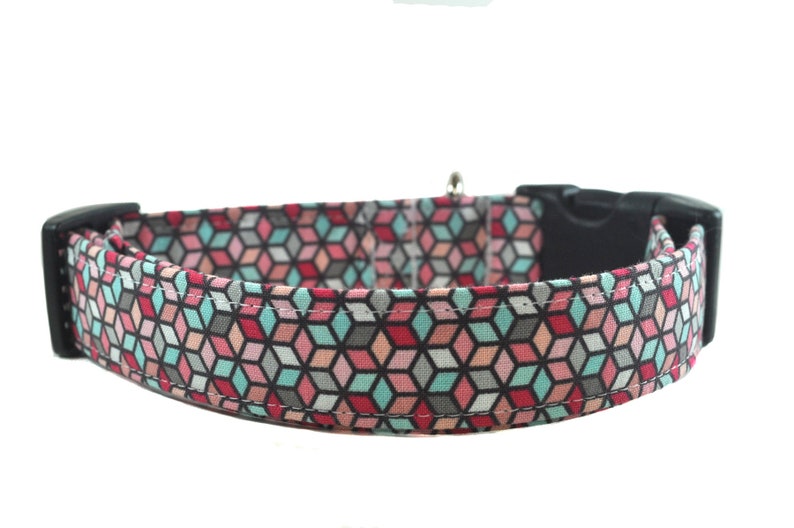 Op de afbeelding: Een hondenhalsband met een geometrisch patroon in roze, blauw en grijs met een zwarte plastic gesp.