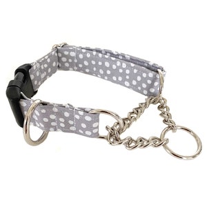 Pode incluir: Um colar de cachorro cinza e branco com bolinhas, uma corrente prateada e uma fivela preta.