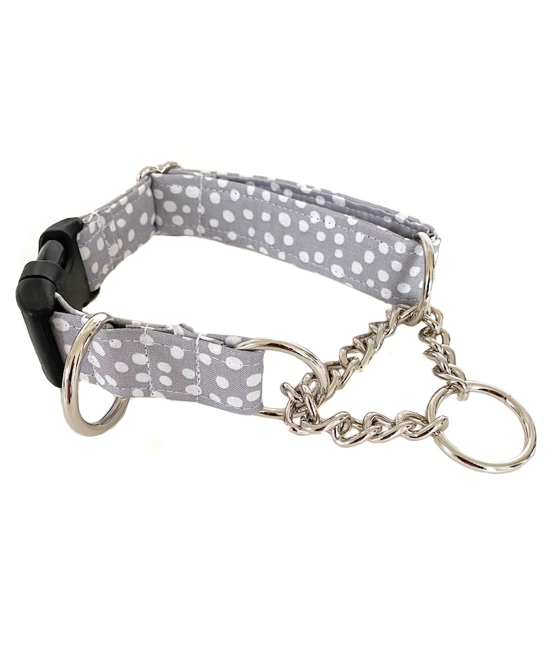 Pode incluir: Um colar de cachorro cinza e branco com bolinhas, uma corrente prateada e uma fivela preta.