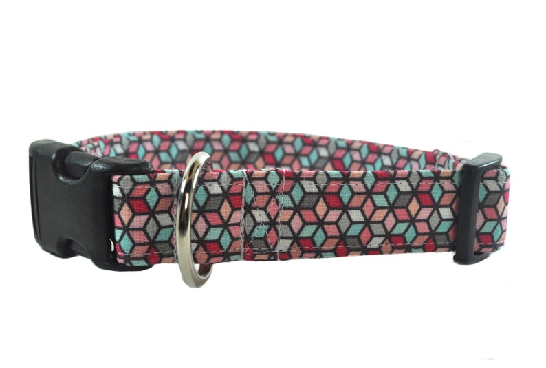 Op de afbeelding: Een hondenhalsband met een geometrisch patroon in roze, blauw en grijs met een zwarte gesp en een zilveren D-ring.