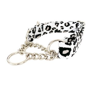 Puede incluir: Un collar de perro de estampado de leopardo blanco y negro con una cadena plateada y dos anillos plateados.
