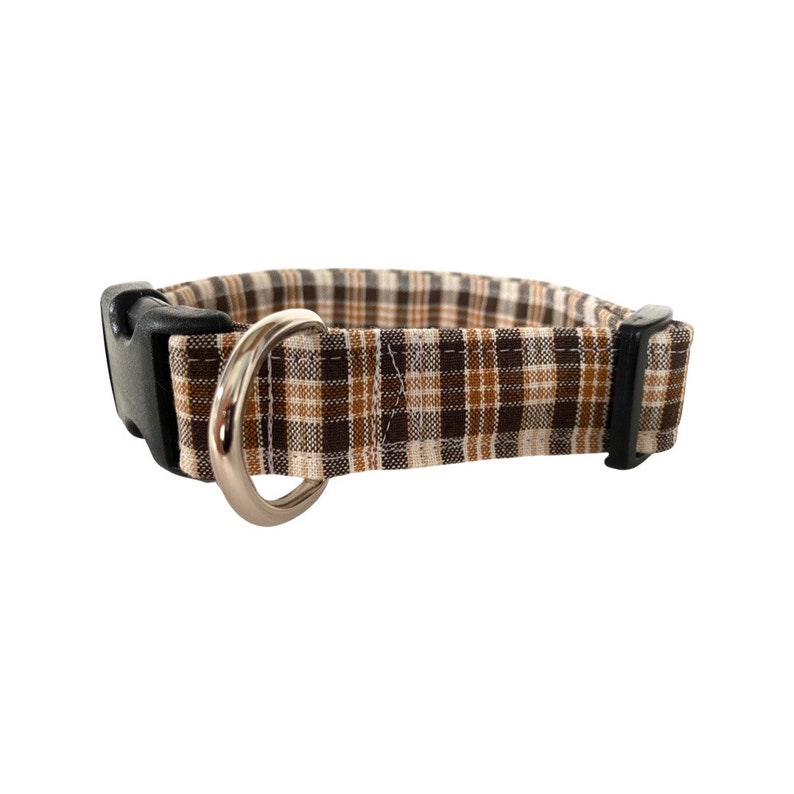May include: A brown and beige plaid dog collar with a black buckle and silver D-ring.