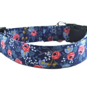 May include: A blue dog collar with a floral pattern featuring pink and red roses. The collar has a black plastic buckle.