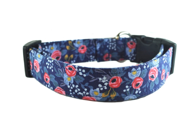 May include: A blue dog collar with a floral pattern featuring pink and red roses. The collar has a black plastic buckle.