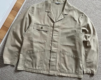 Può includere: Giacca da lavoro beige con collo e quattro tasche frontali. La giacca ha una chiusura con bottoni sulla tasca superiore e una vestibilità rilassata. Realizzata in tessuto resistente, adatta al lavoro o al tempo libero.
