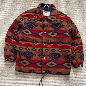 May include: A brown, red, blue, and gold patterned fleece jacket with a snap closure and a drawstring at the bottom. The jacket has a label that says "dublin" on it.