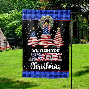 May include: A Christmas garden flag with a black background and a blue plaid border. The flag features three Christmas trees with the American flag design, a wreath, and the text "WE WISH YOU. AMERI Christmas."