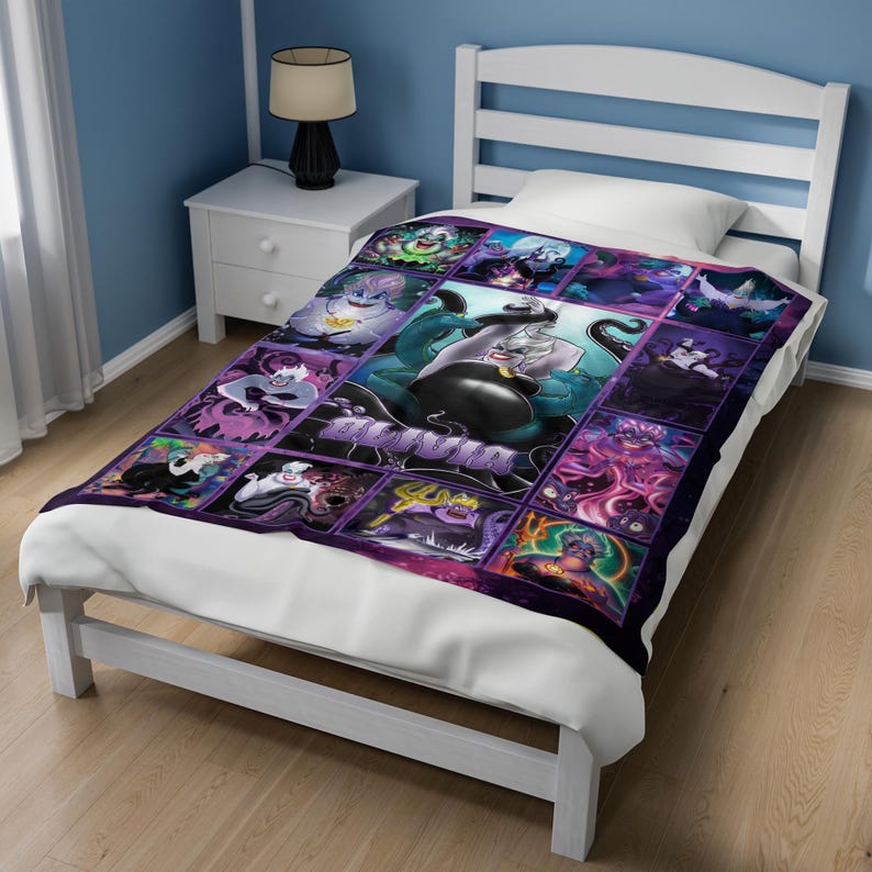 Op de afbeelding: Een paars en zwart sprei met een collage van afbeeldingen van Ursula uit De Kleine Zeemeermin. De centrale afbeelding toont Ursula met haar tentakels. De deken ligt op een wit bed.