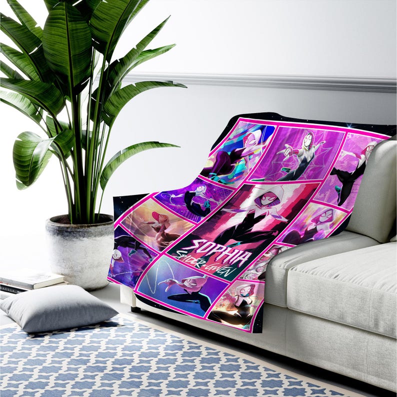 May include: A plush blanket featuring a comic book style design with the text "SOPHIA SPIDER GWEN". The blanket showcases a collage of Spider-Gwen illustrations in shades of pink, purple, and black, draped over a white sofa.
