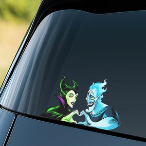 May include: A car window decal featuring cartoon characters Maleficent and Hades forming a heart shape with their hands. Maleficent is in a green and black outfit, and Hades is blue with fiery hair.