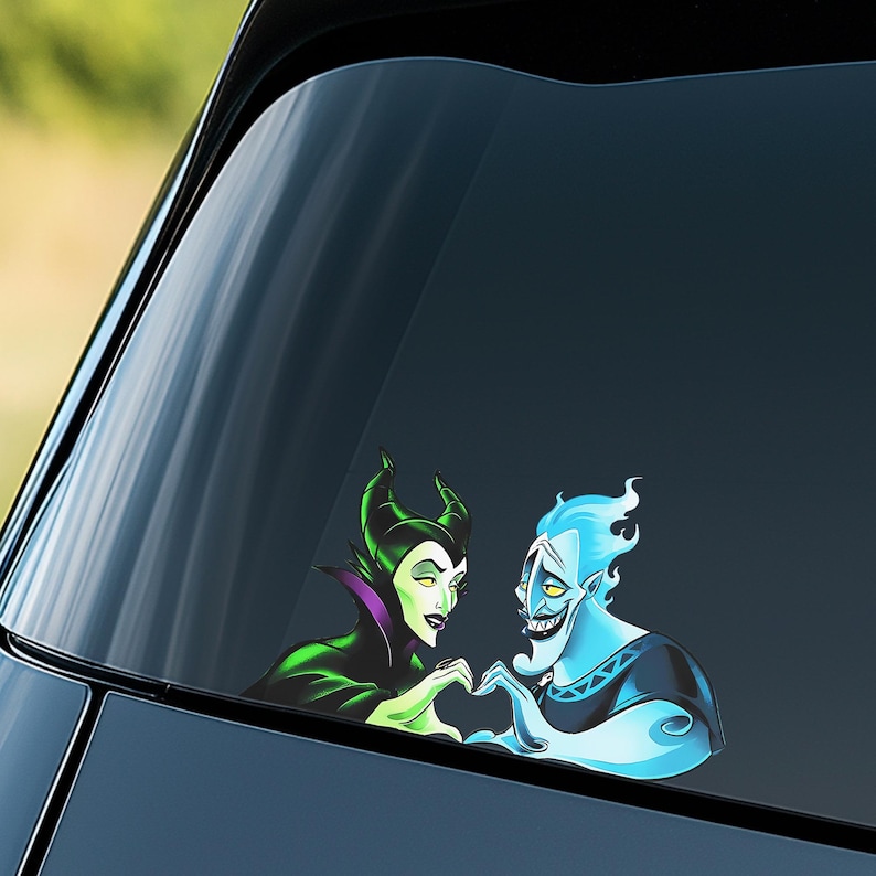 May include: A car window decal featuring cartoon characters Maleficent and Hades forming a heart shape with their hands. Maleficent is in a green and black outfit, and Hades is blue with fiery hair.