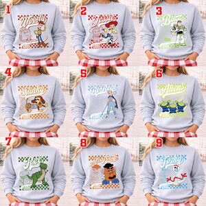 Pode incluir: Uma cole&ccedil;&atilde;o de nove camisolas cinza claro, cada uma com um personagem diferente do filme de anima&ccedil;&atilde;o "Toy Story". Os designs incluem Woody, Jessie, Buzz, Slinky, Bo Peep, Aliens, Rex, Mr. Potato Head e Forky, com o ano de 1995.