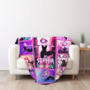 May include: A throw blanket featuring a collage of Spider-Gwen illustrations in a grid pattern. The blanket is predominantly pink, purple, and black, with the name "SOPHIA SPIDER-GWEN" prominently displayed. The blanket is draped over a white sofa.
