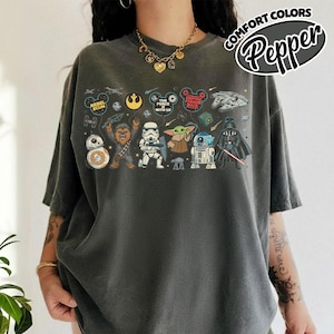 Puede incluir: Camiseta gris oscuro con un dise&ntilde;o de Star Wars. El dise&ntilde;o incluye personajes como BB-8, Chewbacca, un Stormtrooper, Grogu, R2-D2 y Darth Vader. La camiseta tambi&eacute;n tiene el texto "REBEL SCUM", "THE FORCE IS WITH US" y "EMPIRE STRIKES BACK".