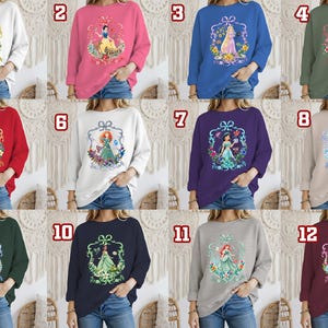 Puede incluir: Colecci&oacute;n de sudaderas de cuello redondo en varios colores, cada una con un gr&aacute;fico de princesa diferente dentro de un marco decorativo. Los colores incluyen blanco, rosa, azul, verde, rojo, morado y gris. Los dise&ntilde;os de princesas est&aacute;n rodeados de elementos florales.