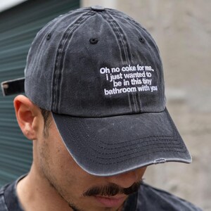 Peut inclure: Casquette de baseball noire délavée avec la phrase brodée : "Oh no coke for me, I just wanted to be in this tiny bathroom with you." La casquette a une visière incurvée et une sangle réglable.