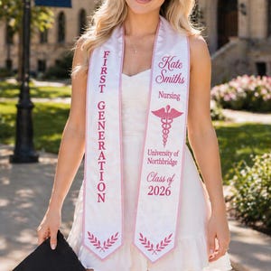 May include: A smiling person wearing a white dress and a graduation sash. The sash is white with pink text that reads "FIRST GENERATION" and "Kate Smiths Nursing University of Northbridge Class of 2026". The person is holding a black graduation cap.