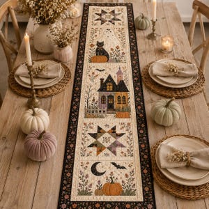 May include: A rectangular fabric table runner featuring a patchwork design with Halloween-themed illustrations including a haunted house, a black cat, a ghost, pumpkins, stars, and a crescent moon, all bordered by a dark floral pattern on a cream background.