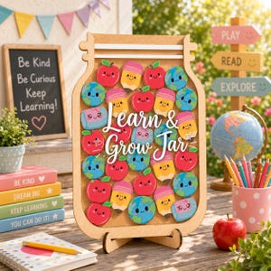 Könnte beinhalten: Ein hölzernes Learn & Grow Jar-Display mit bunten, lächelnden Symbolen von Äpfeln, Bleistiften, Globen und Radiergummis. Das glasförmige Brett steht auf einem Ständer und enthält verschiedene kleine, illustrierte Plättchen mit fröhlichen Gesichtern.