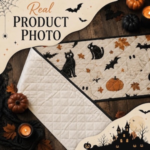May include: A quilted table runner featuring a cream-coloured fabric with a repeating pattern of black cats, orange pumpkins, white ghosts, bats, and brown autumn leaves. The runner has a diamond-stitched texture and a solid cream-coloured underside.