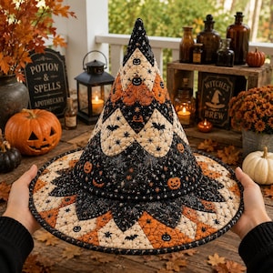 May include: A quilted witch hat featuring a patchwork design of orange, black, and cream fabric. The pattern includes motifs of jack-o'-lanterns, spiders, bats, and spiderwebs. The hat has a pointed crown and a wide, circular brim with stitched details.