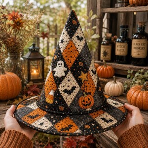 May include: A quilted witch hat featuring a black and orange diamond pattern with appliqued motifs including a white ghost, a yellow star, a jack-o'-lantern, and candy corn, accented with small black bats, spider webs, and stars throughout.