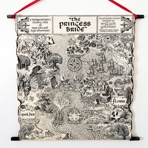 May include: A black and white map of the fictional world from "The Princess Bride" with the title at the top. The map is printed on aged paper and is suspended by a red ribbon. The map includes text and illustrations.