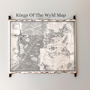 May include: A framed map titled "Kings Of The Wyld Map" with a detailed black and white illustration of a fantasy world. The map has a parchment-like appearance with a decorative border and wooden accents.