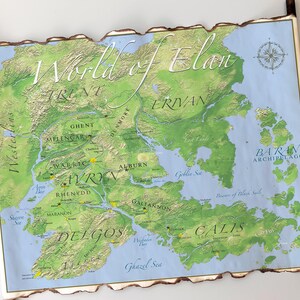 May include: A detailed map titled "World of Elan" with a fantasy theme. The map features green landmasses, blue oceans, and various place names. The map is framed with a wooden border and has a scroll-like appearance.