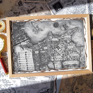 Peut inclure: Une carte en noir et blanc encadrée d'une ville, avec le mot "KETTERDAM" en bas. La carte est dans un cadre en bois brun clair. Une loupe avec un manche rouge et une boussole sont sur la table.