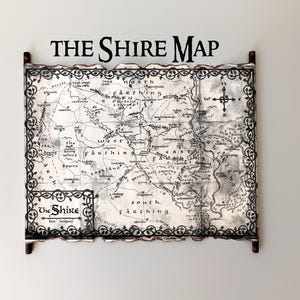 May include: A map of The Shire, with the title "THE SHIRE MAP" at the top. The map is in black and white, with a decorative border. The map is mounted on wooden dowels.