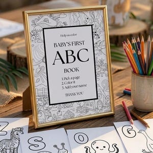 May include: A gold-framed sign with black text reading Help us color BABY'S FIRST ABC BOOK 1.Pick a page 2.Color it 3.Add your name THANK YOU, surrounded by black and white line art illustrations, with coloring pages and colored pencils nearby.