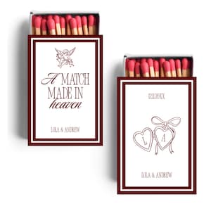 May include: Two matchboxes with red match heads. One box has the text "A MATCH MADE IN heaven" and "LOLA & ANDREW". The other box has the date "12.11.20XX" and the initials "L" and "A" inside hearts, with "LOLA & ANDREW" below.